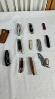 Full lot of 11 vintage multi-purpose pocket tools, including knives, multi-tools, wooden pliers tool, and a leather sheath.