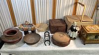 Full view of all items in the collection spread on a table including wicker baskets, wooden painted decorative pieces, pottery, and figurine.
