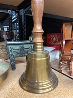 Brass captain's bell with turned wooden handle sitting on shelf