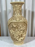 Front view of the carved composite vase showing floral and bird relief details on the body