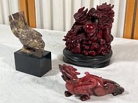 Photo showing all three items: composite dragon on black base, stone dragon figurine, and soapstone bird on pedestal