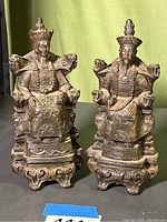 Pair of composite Chinese man and woman sitting figurines on decorative bases, showing full bodies and intricately carved details.