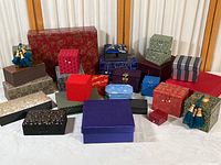 Full view of collection showing a variety of fabric and paper covered boxes in different shapes, sizes and colors including red, blue, green, black, purple and patterned colors.