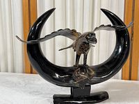 Front and side view of carved eagle sculpture perched on crescent-shaped stand