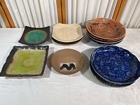 Full spread showing all 14 Far Eastern stoneware plates and bowls arranged on table in several stacks organized by design.
