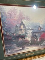 Close-up photo of the framed print showing the cottage with blooming foliage and the title plaque at the bottom center.
