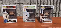 Photo showing all three Funko Pop figures in their original boxes against a brick wall background.