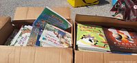 Two cardboard boxes filled with various children's books including Pokémon, Crazy Cat, Planet Earth, and more, showing the lot contents visually.