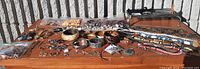Wide view of assorted costume jewelry laid out on wooden table, showing bracelets, necklaces, bangle sets, and earrings.