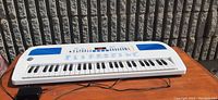 Full view of the white Discovery Kids electronic keyboard with 37 black and white keys, control buttons, and a small screen.
