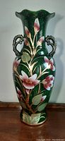 Front view of the green floral floor vase with ornate handles and handpainted pink flowers.