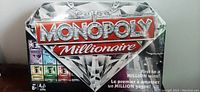 Front of sealed Monopoly Millionaire board game box showing logo, diamond graphic, and partial game board layout.
