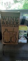 Photo of the closed Wine & Beer Starter Kit cardboard box showing illustration of included items like glass carboy, bucket, airlock, and stirrer.