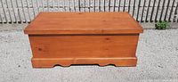 Closed wooden blanket box showing natural wood finish, front view with base molding and slight scratches on top.