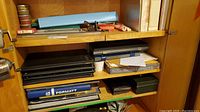 Three-shelf cabinet view with binders, box, precision components and papers