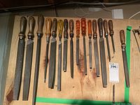 Full view of the 14 pieces hand files and rasps laid out on wood surface, showing variety in handle material and file types.