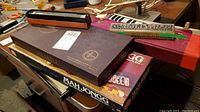 Photo showing stacked board game boxes including Scrabble and Mah Jongg, a harmonica, and Horner Melodica keyboard instrument in its box