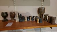 Shelf display of onyx chess pieces, goblets, and bud vases with varying colors including black, white, gray, and beige tones.