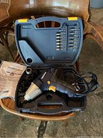 Mastercraft impact drill with bits and sockets in carry case, shown open on wooden chair, includes instruction paper.