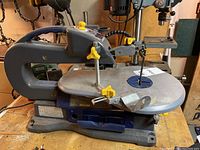 Mastercraft Maximum 16-inch scroll saw sitting on a workbench showing the side profile and table.