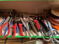 Tools arranged on a shelf including pliers, snippers, scissors, and buffing wheel at the right side.