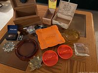 Various cigar boxes, ashtrays in multiple materials and colors, and cigar cutters arranged on a table.