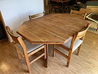 Wooden octagonal kitchen table with four chairs around it on wood floor, showing overall setup and condition