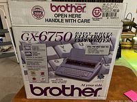 Closed retail box showing front and top with 'Brother Correctronic GX-6750 Daisy Wheel Electronic Typewriter' branding, features and image of the typewriter.