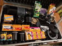 Open case showing camera body, lenses, film boxes, converters, filters, cloth and canisters