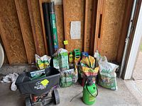 Photo shows Scotts Turf Builder broadcast spreader and multiple bags of soil, fertilizer, compost, weed barrier, stakes, and liquid revive bottles.