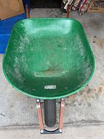 Top view of the green plastic tub of the wheelbarrow showing some wear and dirt marks.