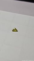 Top and side angle showing the triangular shape and color of the sphene gemstone on a white background.