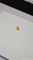 Photo of a single heart cut canary yellow sapphire gemstone on a white background