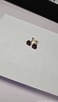 Pair of cherry red garnet stud earrings on a white surface, showing front view