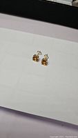 Photo of golden citrine stud earrings on white surface showing front and side views.
