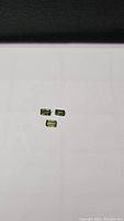 Photo of three emerald cut natural green sapphires on a white background shown from a distance.