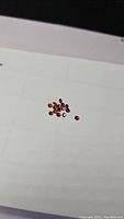 Photo showing a small group of loose orange red diamond cut gemstones on a white surface.