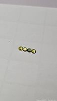 Four natural round-cut sapphires placed in a line with bright greenish yellow coloration.