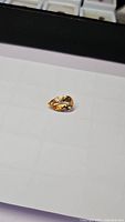 Close-up image of pear-shaped natural golden citrine gemstone placed on a white surface showing its clarity and cut