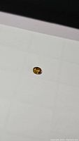 Oval cut yellow sapphire gemstone placed on white background showing its size, shape, and color.