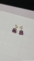 Pair of small amethyst stud earrings with sterling silver posts and backs shown on white background, one showing front face and one showing side angle.