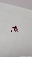 Small collection of loose round cut rubies with rich red color on a white background.