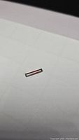 Close-up image of elongated baguette cut watermelon tourmaline gemstone on white background showing its dual pastel colors and clarity.