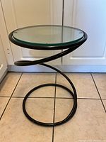 Front view showing the spiral metal base and the round glass top of the side table.