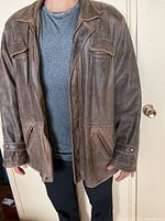 Front view of brown leather coat worn by model showing fit and style