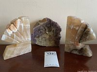 Full set showing purple quartz clock flanked by fan-shaped carved stone bookends in beige tones.