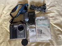 Top view of Sony Digital Mavica camera with accessories including strap, lens cap, charger, power cord, and manual.