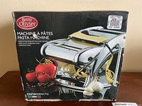 Box front showing stainless steel pasta maker with fresh tomatoes and garlic pictured, brand Remy Olivier, Pastaperfecto line.
