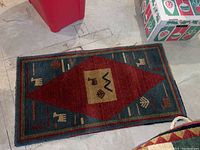 Small rectangular area rug with large central diamond in red and blue with animal and plant motifs