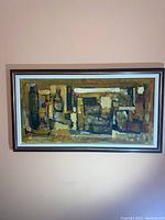 Front view of larger framed abstract painting with geometric shapes in earth tones.
